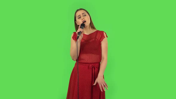 Tender Girl in Red Dress Is Singing Into a Microphone and Moving To the Beat of Music. Green Screen