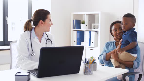 Mother with Baby and Doctor with Laptop at Clinic