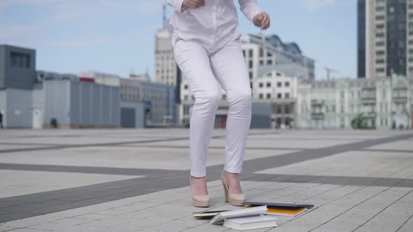 Legs of Young Slim Woman Dropping Sketchbooks in Slow Motion on City Square Outdoors