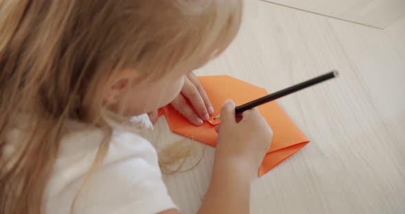 A Girl in Kindergarten or at Home Paints a Figure Out of Paper