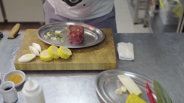 Unrecognized Chef in Apron Pouring Raw Piece of Meat with Seasoning Before Baking in the Oven