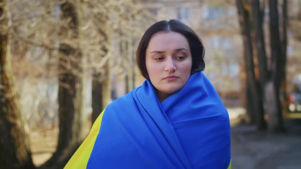 Portrait of a Sad Ukrainian Woman with a Ukrainian Flag and a Sign