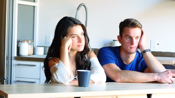 Thoughtful couple sitting in kitchen