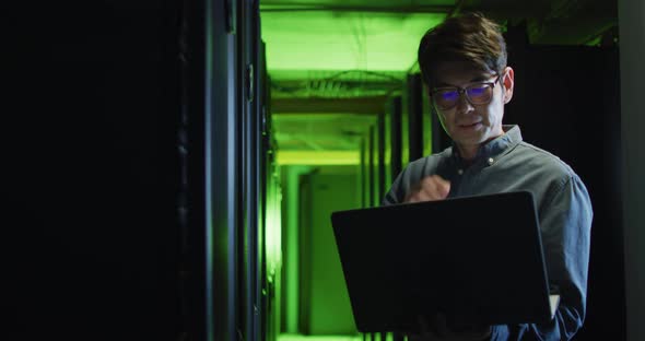 Asian male it technician using laptop checking computer server