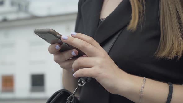 Close-up of Young Female Hands Using Smartphone Outdoors. Unrecognizable Caucasian Woman Messaging
