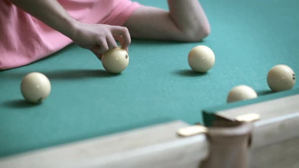 A Man Lying on a Billiard Table Plays with Billiard Balls Rolls Them Into a Pocket Closeup