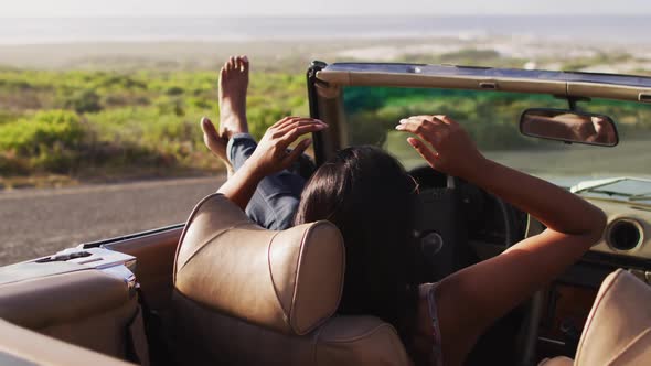 African american woman sitting with her feet on the window of convertible car