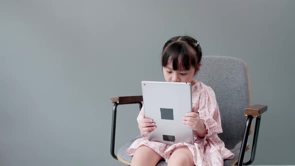 Child watching digital tablet and looking at cheerful camera.