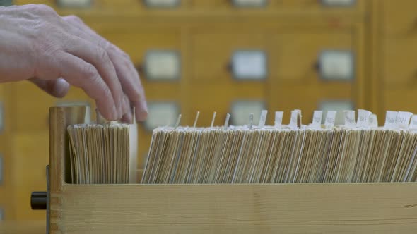 A Male Hand Searching Cards in Old Wooden Card Catalogue