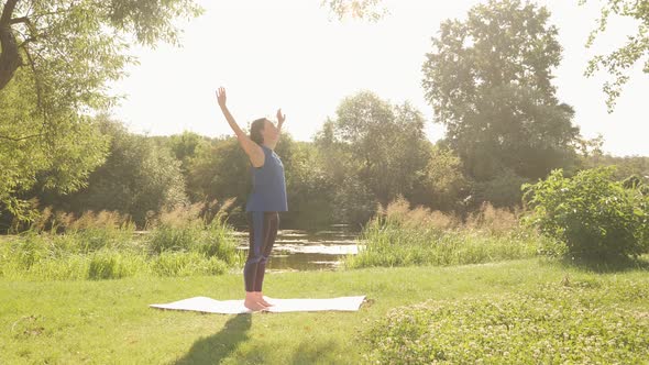 Woman exercising in park in the morning. Female doing meditation exercises at sunrise