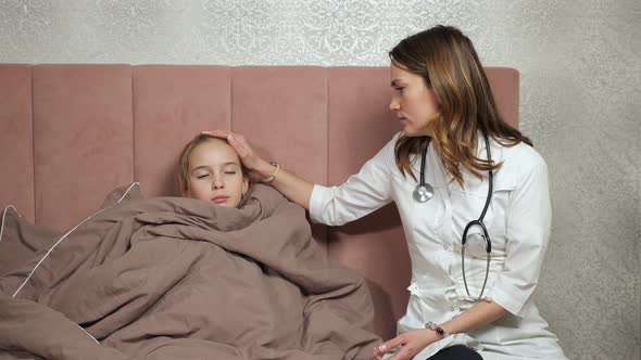 Doctor Touches Forehead of Teen Girl Checking Temperature