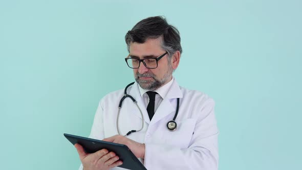 Senior Doctor 50s Works in Tablet on Blue Background