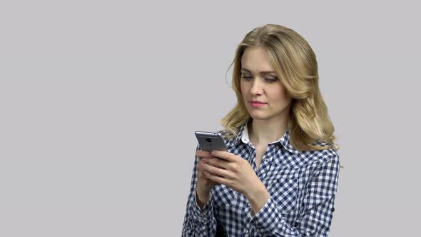 Young Blond Woman Typing Message on Her Smartphone