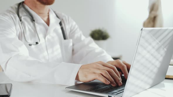 Midsection of Male Physician in Lab Coat Working on Laptop