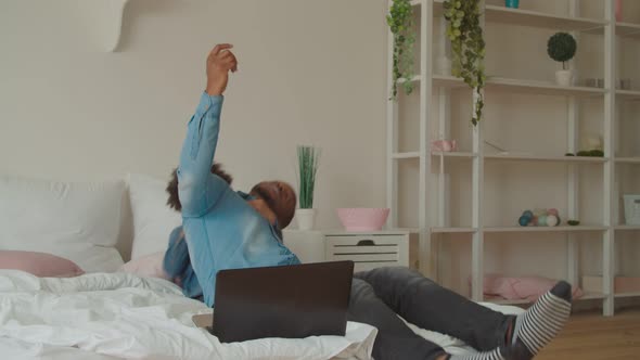 Playful Son Embracing Busy Black Dad in Bedroom