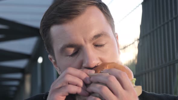 Businessman During Lunch Break Eating Hamburger or Sandwich Close Up Standing Near Business Center