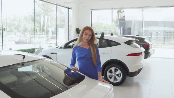 Beautiful Woman Examining Expensive Car at the Dealership