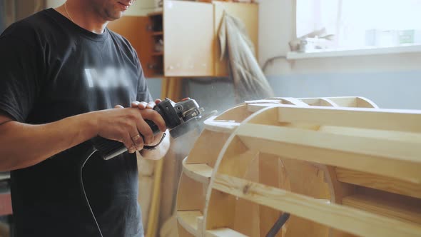 A Professional Carpenter Working with Wood on a Woodworking Machine Grinds and Polishes Wood
