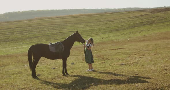 Happy Slavic Woman in Dress Caresses a Brown Horse Among the Wide Steppes