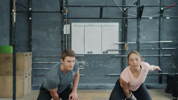 Man and Woman Lifting Kettlebells Training in Gym Together Busy with Sports Exercise