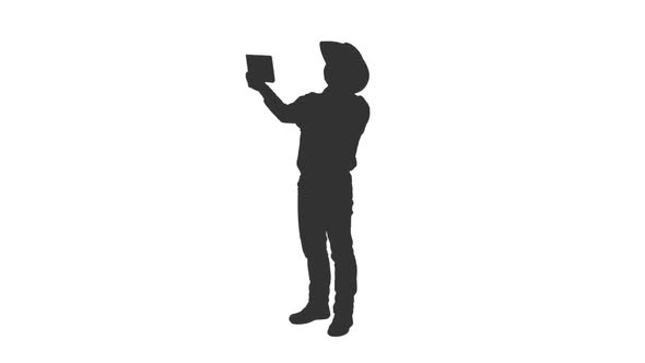 Silhouette of Man Tourist in Cowboy Hat Taking Selfie  alt