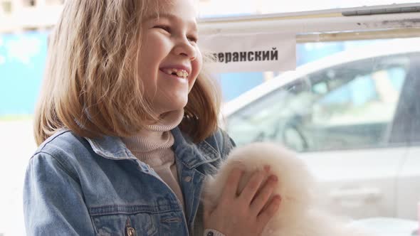 a Small and Happy Girl with a White and Fluffy Spitz Puppy