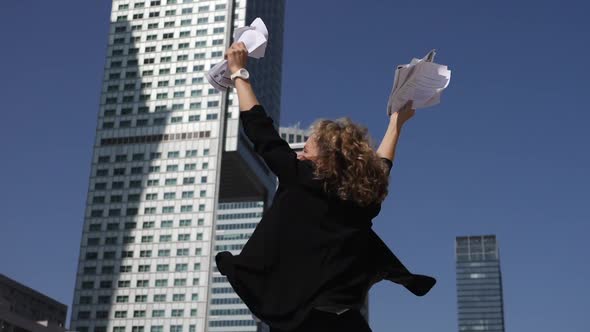 Young Career Woman Extremally Excited for Her Professional Success Jumps Holding Papers in Hands