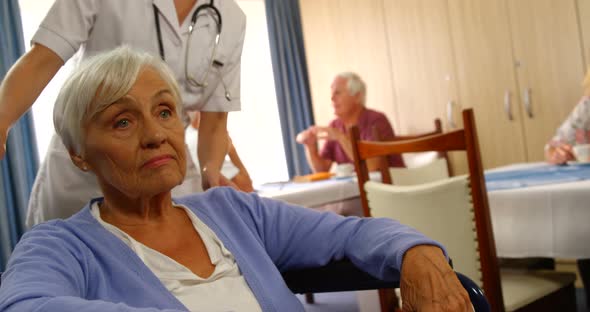 Doctor talking to senior woman sitting in wheelchair