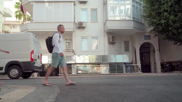 A Man and a Woman Walk Down the Street One After Another