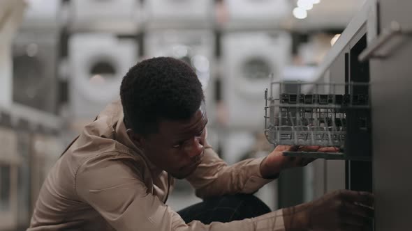 Single Black Man is Buying Dishwasher in Home Appliances Store Viewing Kitchen Equipment