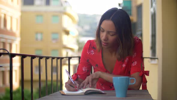 A woman writing in a journal diary traveling in a luxury resort town in Italy, Europe.