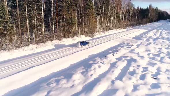 Aerial view of a car driving in the snowy forest in Estonia.