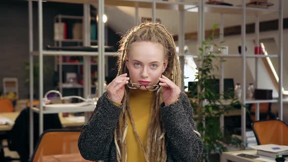  Young Woman with Dreadlocks Putting on Her Glasses and Looking at Camera