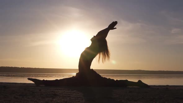 Silhouette of a Beautiful Yoga Girl at Sunrise on the Beach