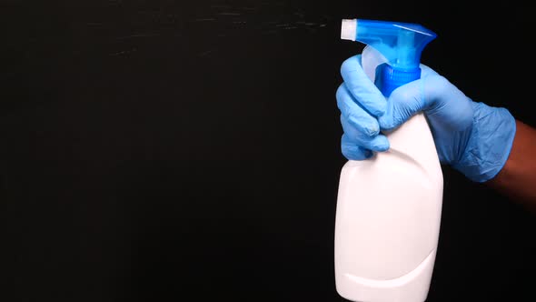 Hand in Disposable Gloves Using Disinfectant Isolated on Black 