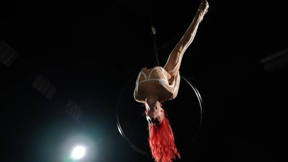 Bottom Angle View of Smiling Beautiful Woman Hanging on Air Hoop Spinning with Backlit at Black