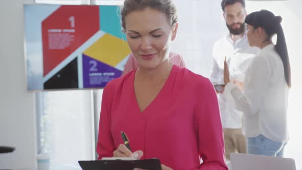 Portrait of happy caucasian businesswoman over diverse colleagues in office