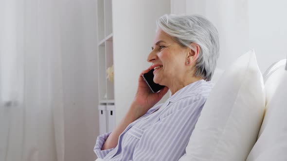 Senior Woman Calling on Smartphone in Bed at Home