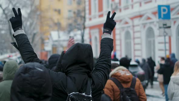 Peaceful Activists with Peace Sing Fingers Walking on Winter Snowing City Street