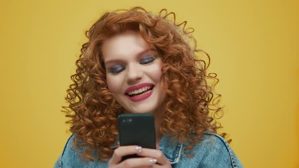 Woman Texting on Smartphone. Girl Using Mobile Phone on Yellow Background