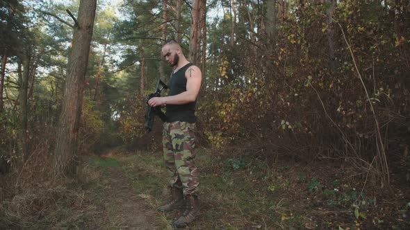 The Fighter Infects a Gun and Aims at an Object in the Woods at Sunset