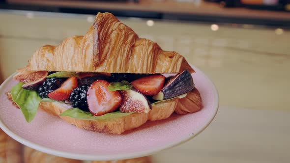 Beautiful Crispy Golden Berry Croissant with Strawberries Blackberries and Basil on Pink Plate
