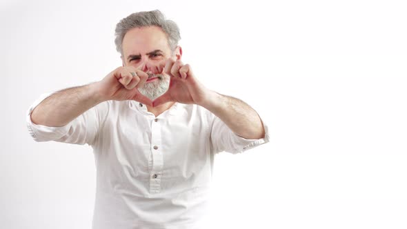 Elderly Caucasian Man Making a Heart Shape More in Front of His Body to Show His Affection White