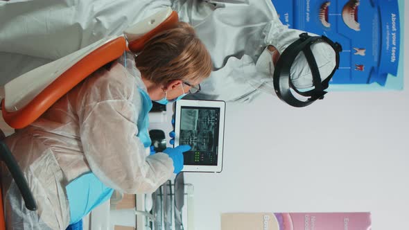 Vertical Video Dentist in Coverall Examining Xray Image on Tablet