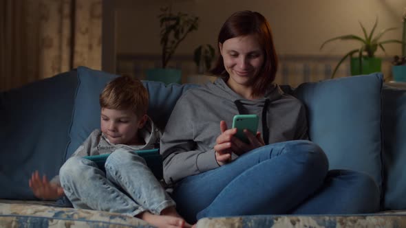 Family using gadgets sitting on couch at home