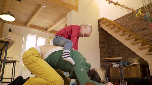 Father playing with adorable infant son at the floor of living room.