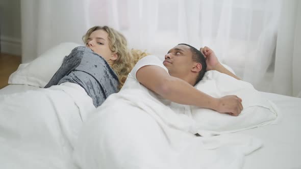 Argued Interracial Young Couple Lying in Bed Back to Back