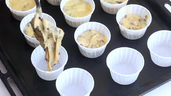 A Woman Puts The Dough Into Muffin Tins On A Baking Sheet.