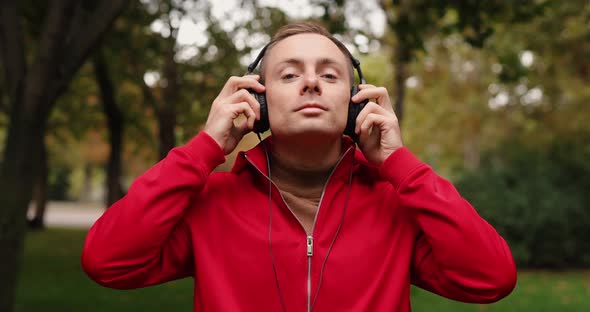 Man in Red Jacket Wearing Headphones at the Autumn Park