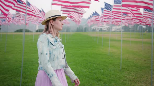 Young Woman in the Urban Green Park with Many American Flagpoles Blowing in Wind